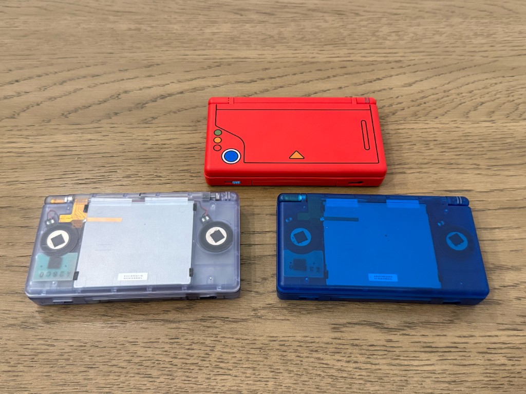 Backs of a clear DS Lite, a blue DS Lite, and a red Pokedex DS Lite after reshelling.