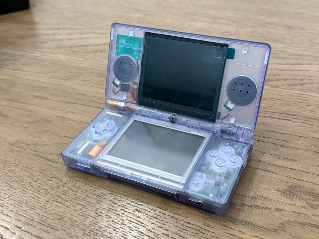 A clear DS Lite opened after a reshell, with the board and speakers visible.
