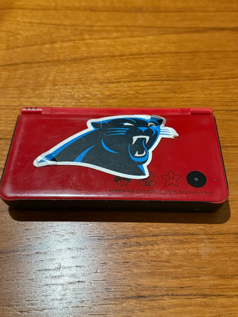 A scratched red DSi XL with a sticker that would not come off the shell.