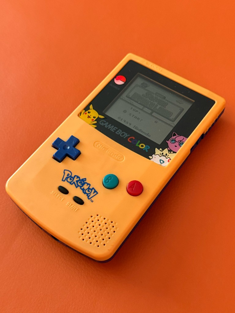 Yellow Pokémon edition Game Boy Color with the original dim screen showing a faint Super Mario Land title.